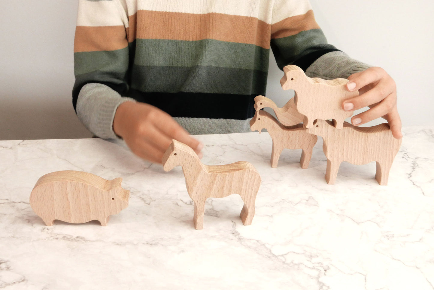 Niño jugando con animales de madera de la granja