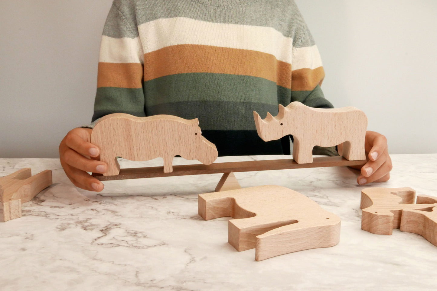 Niño equilibrando animales de madera en una barra