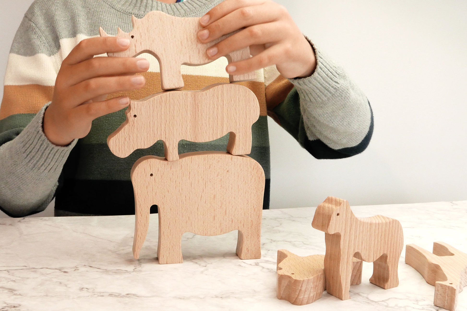 Niño haciendo una torre con animales de madera