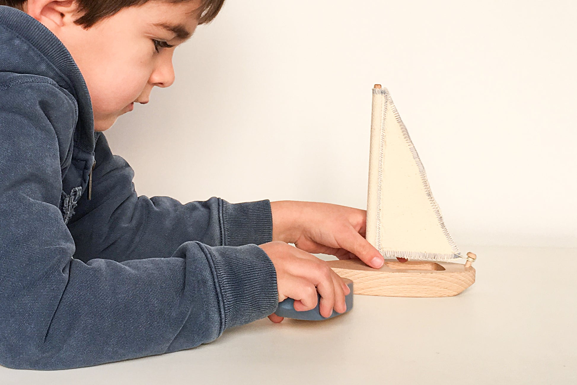 Niño jugando con el velero de madera Kerkus